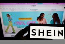Person holding smartphone with logo of e-commerce company Shein on screen in front of website Focus on phone display